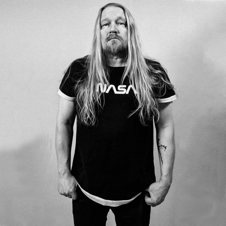 black and white photo of a longhaired and bearded man (Esa Linna) standing in front of the camera